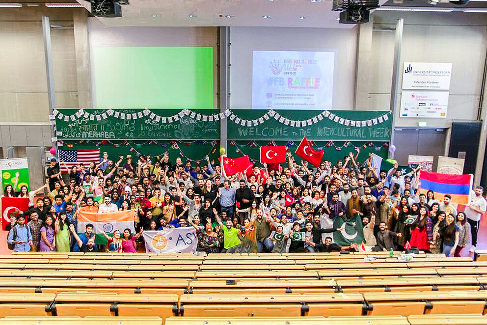 Internationale Studierende mit Flaggen in einem Hörsaal der Universität Paderborn.