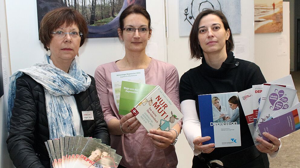 Foto (Universität Paderborn, Heiko Appelbaum): Hildegard Harmeier, Sandra Bischof und Dr. Yvonne Koch (v. l.) werben vor einer Bilderausstellung für einen offensiven Umgang mit der Depression.