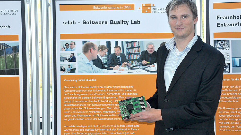 Foto (Jannic Hüsemann): Dipl.-Inform. Daniel Baldin mit einem Evaluationsboard – einem vergrößerten Modell einer Smart Card.