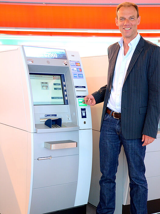 Foto (Stefan Pföhler und Simone Rudolph): Prof. Dr. Johannes Blömer vor einem Geldausgabeautomaten des Projektpartners Wincor Nixdorf.