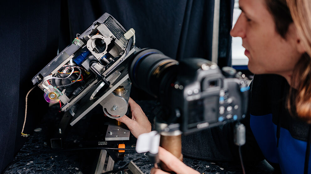 Ein junger Mann tüftelt an einem technischen Gerät.